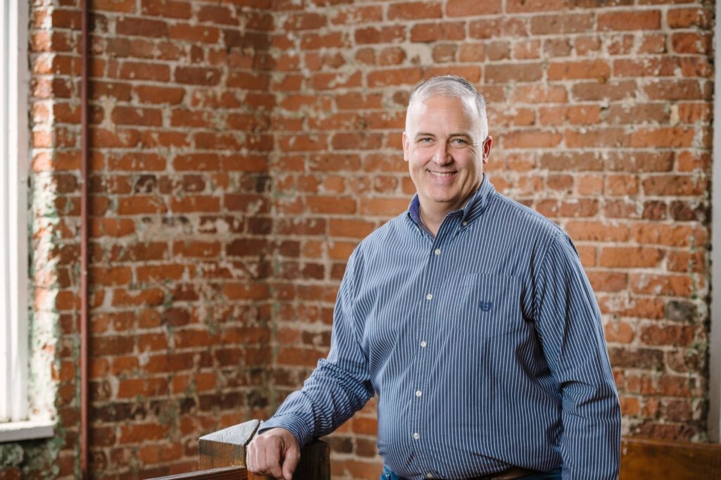 Picture of Eric Beasley standing in front of a brick all