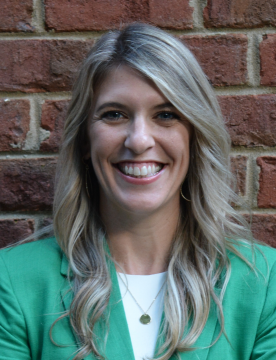 Picture of Kesler Ballew, standing in front of a brick wall with a light green top.